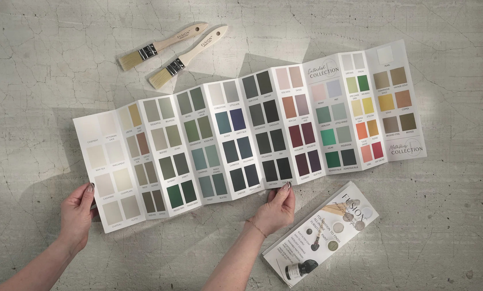 Hands holding a color palette with premium paints and painting tools, ideal for DIY décor and modern home décor projects.