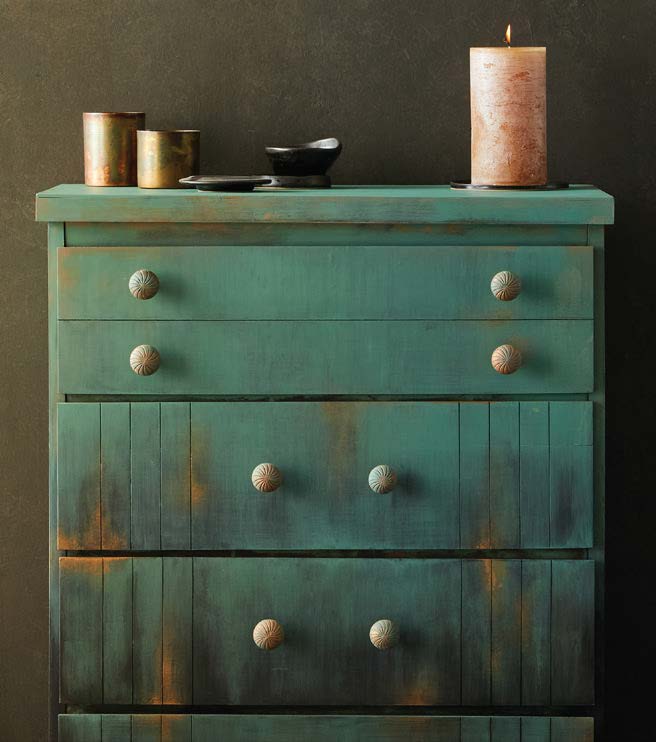 Teal chest of drawers with decorative stencils, candles, and home décor accessories for modern DIY décor.