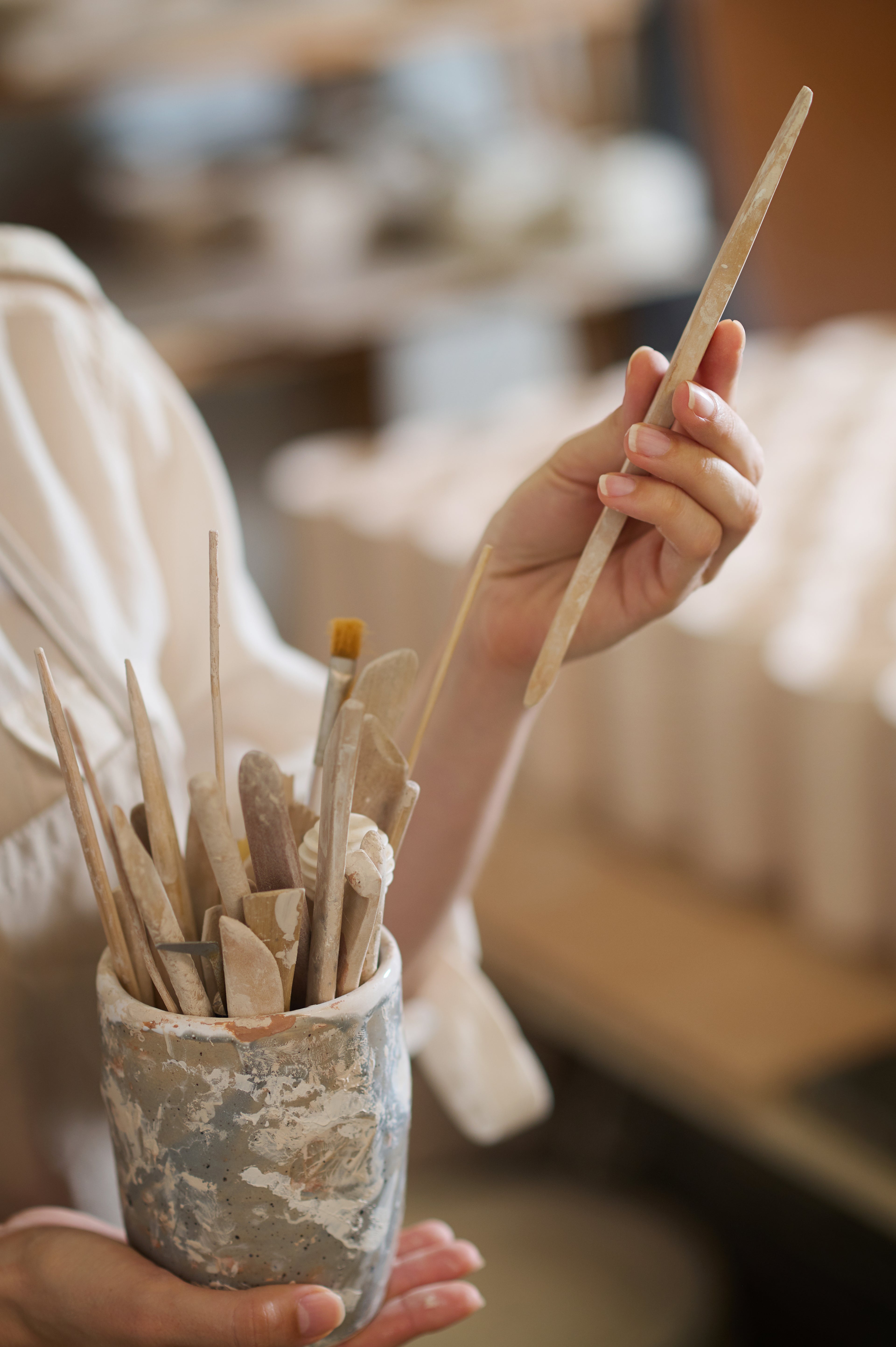 Hand holding a container filled with premium art tools and painting accessories for crafts and DIY home décor projects.