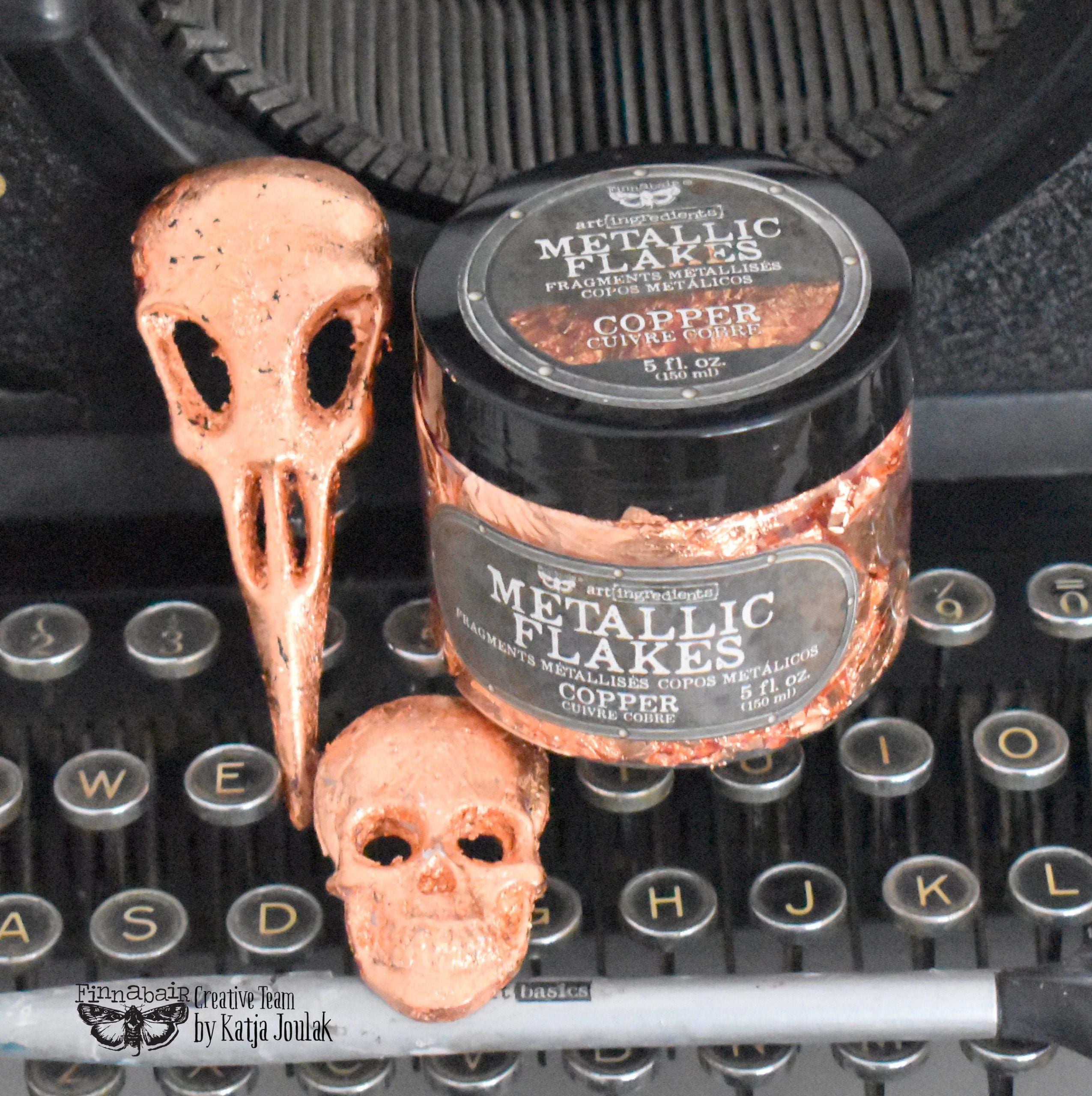 Fine Mica Flakes, Copper jar with shiny metallic flakes next to decorative skulls for DIY décor and creative projects.