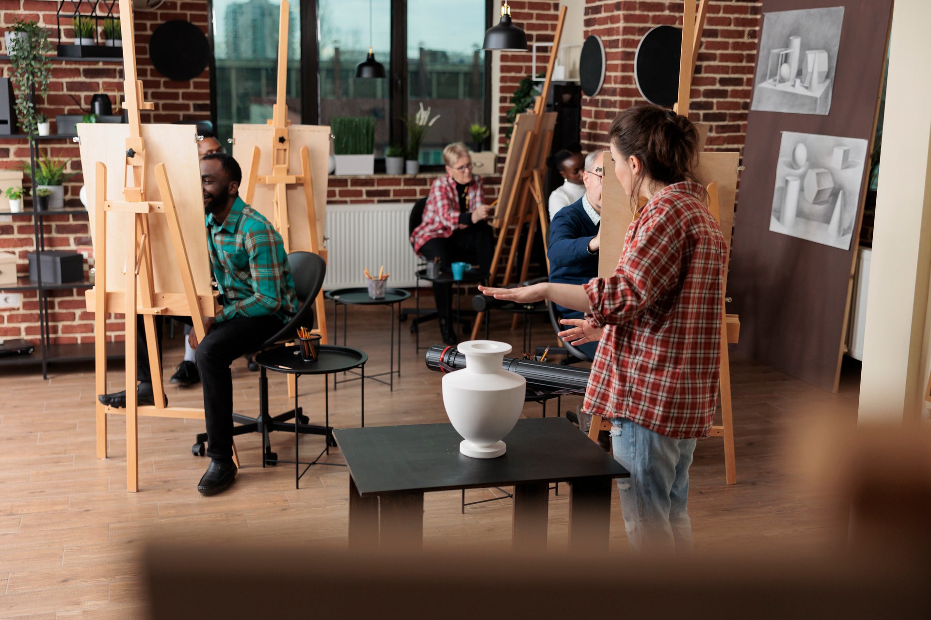 Art class in a studio with students painting and an instructor demonstrating techniques for creative projects.