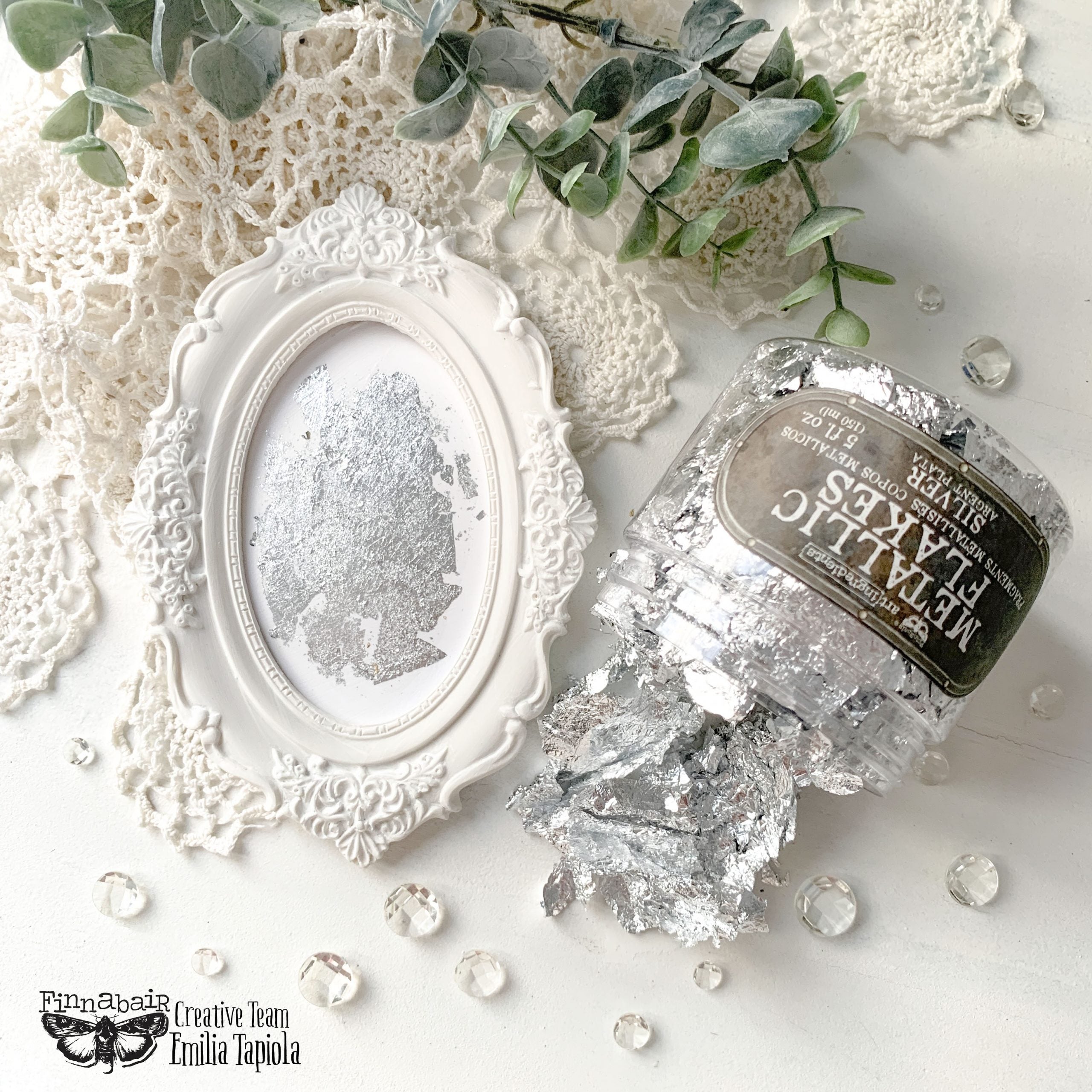 Fine Mica Flakes, Silver in a jar next to a decorative frame, ideal for DIY décor and artistic finishes.